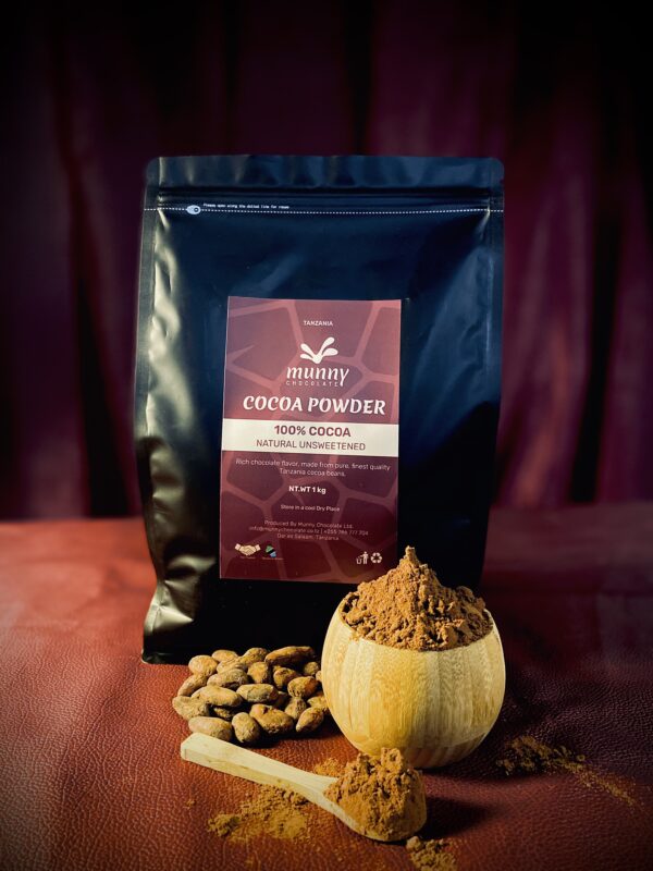 A pouch bag of Tanzania Unsweetened cocoa powder standing with cocoa beans and a wooden bowl of cocoa powder.